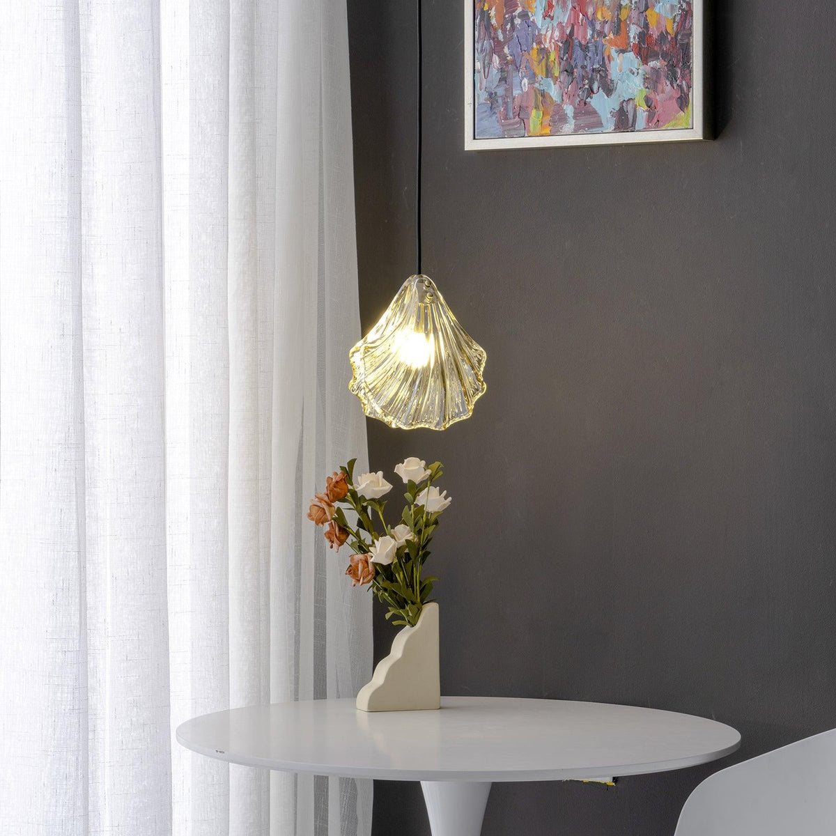 Shelvara Pendant Light, clear shell glass lit over a white round table