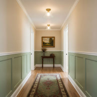 Two of the ceiling lights fitted along a hallway with green panelled walls.