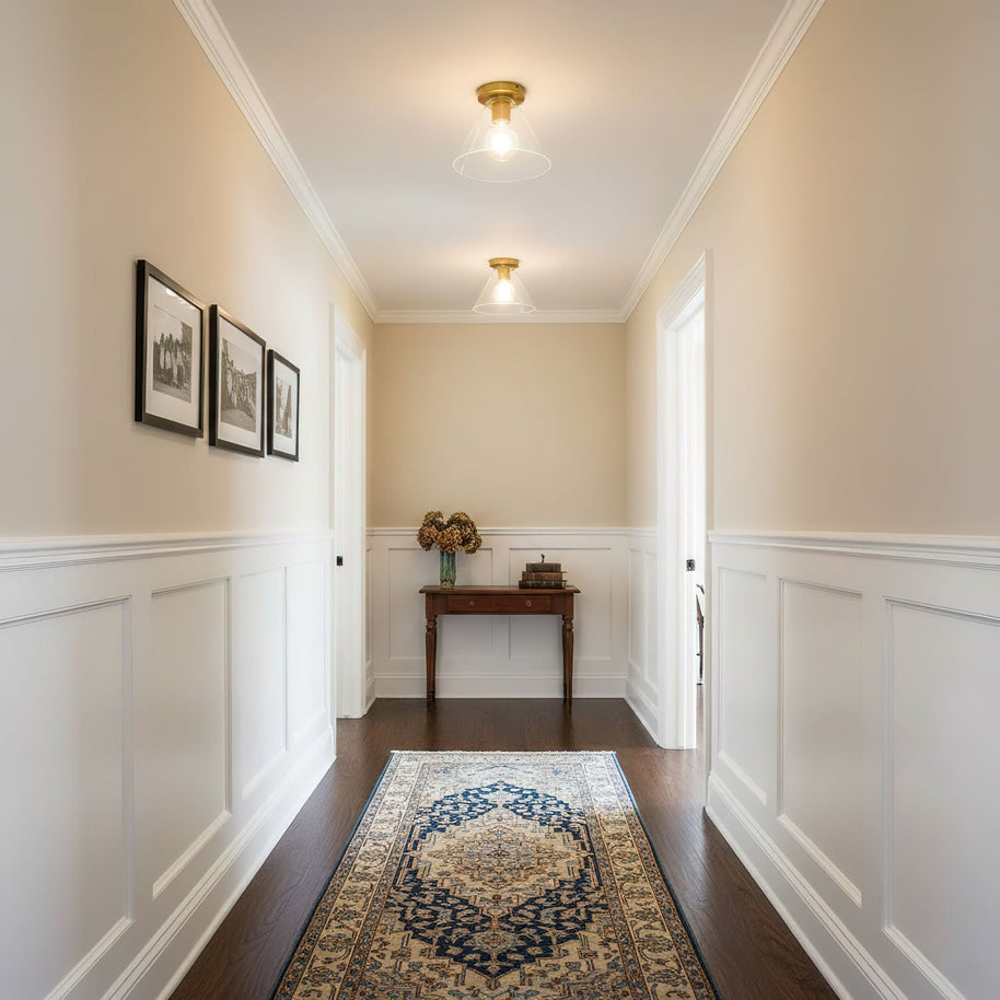 Two of the ceiling lights lit along a hallway with cream walls and white panelling.