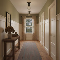 Two of the ceiling lights fitted along a hallway with olive walls.