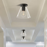 Three of the ceiling lights with dark plates and clear cone shades on a white coffered ceiling.