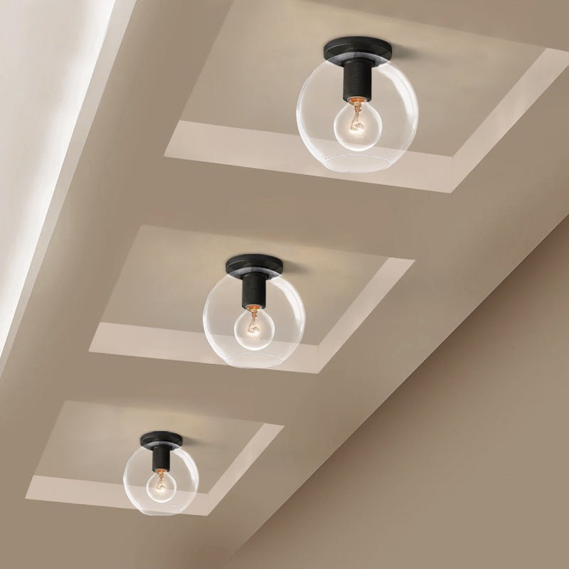 Three of the ceiling lights with dark plates and clear round shades on a beige coffered ceiling.