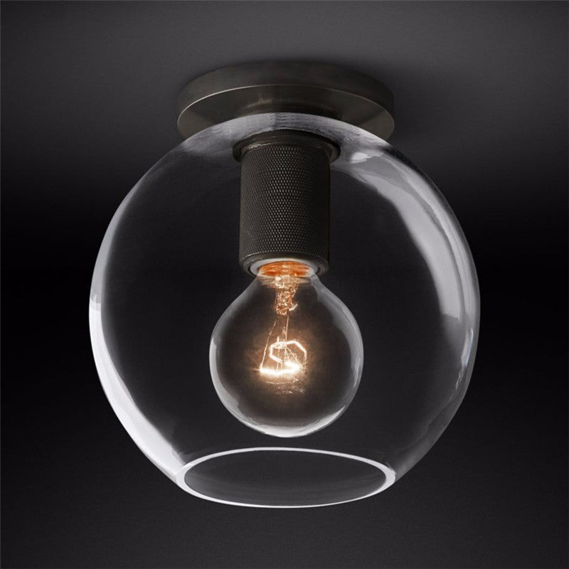 Flush-mount ceiling light with a dark ceiling plate and a clear round glass shade.