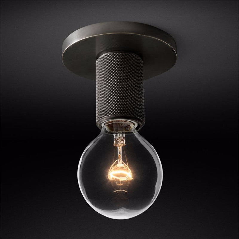 Close view of the dark ceiling plate and knurled holder with the bulb lit.