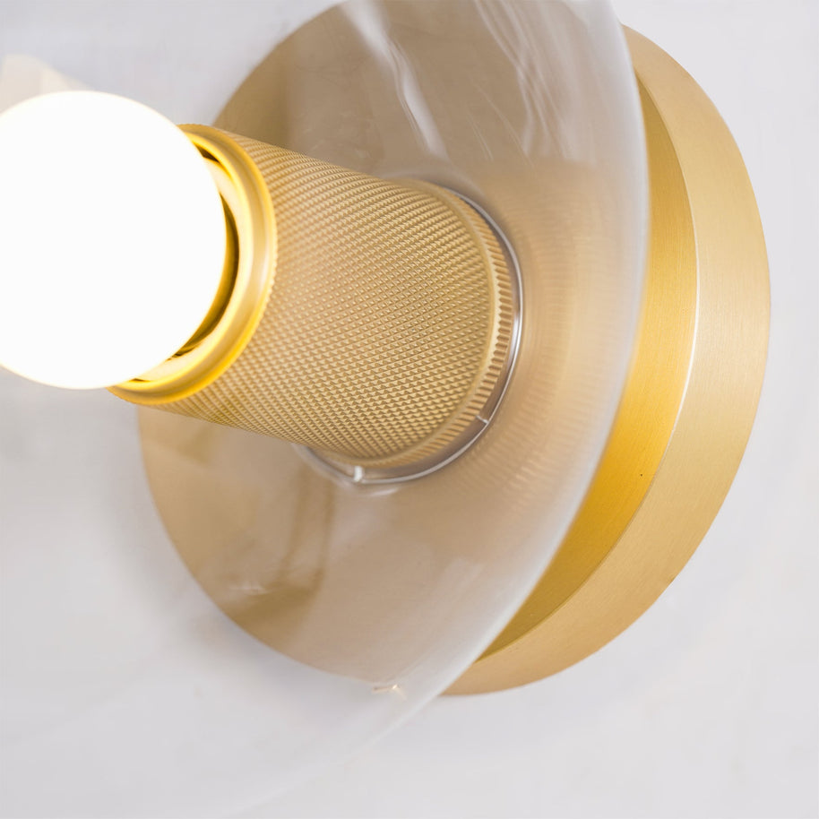 Close view of the knurled gold-toned holder and round back plate with the bulb lit.
