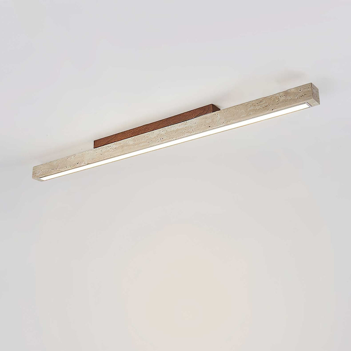 Travellin Ceiling Light, travertine bar with dark walnut mount lit on a pale ceiling