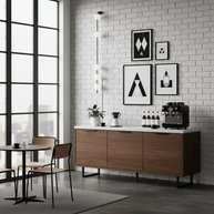 Wall lamp with a vertical row of white ball shades on a slim black rod lit against a white brick wall.