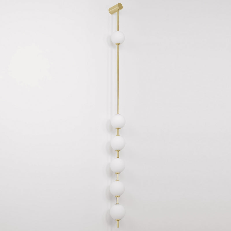 Wall lamp with a vertical row of white ball shades on a slim gold-toned rod, unlit, on a white background.
