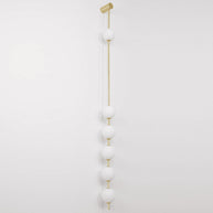 Wall lamp with a vertical row of white ball shades on a slim gold-toned rod, unlit, on a white background.