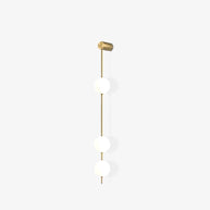 Wall lamp with a vertical row of white ball shades on a slim brass-coloured rod, unlit, on a white background.