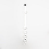 Wall lamp with a vertical row of white ball shades on a slim dark rod, unlit, on a white background, seen straight on.