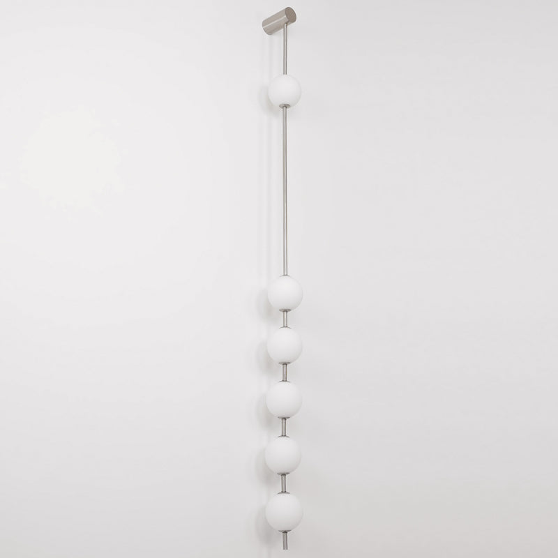 Wall lamp with a vertical row of white ball shades on a slim pale grey rod, unlit, on a white background, seen straight on.