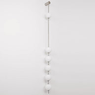 Wall lamp with a vertical row of white ball shades on a slim pale grey rod, unlit, on a white background, seen straight on.
