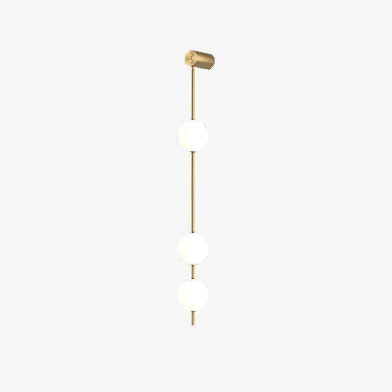 Wall lamp with a vertical row of white ball shades on a slim gold-toned rod, unlit, photographed against white.