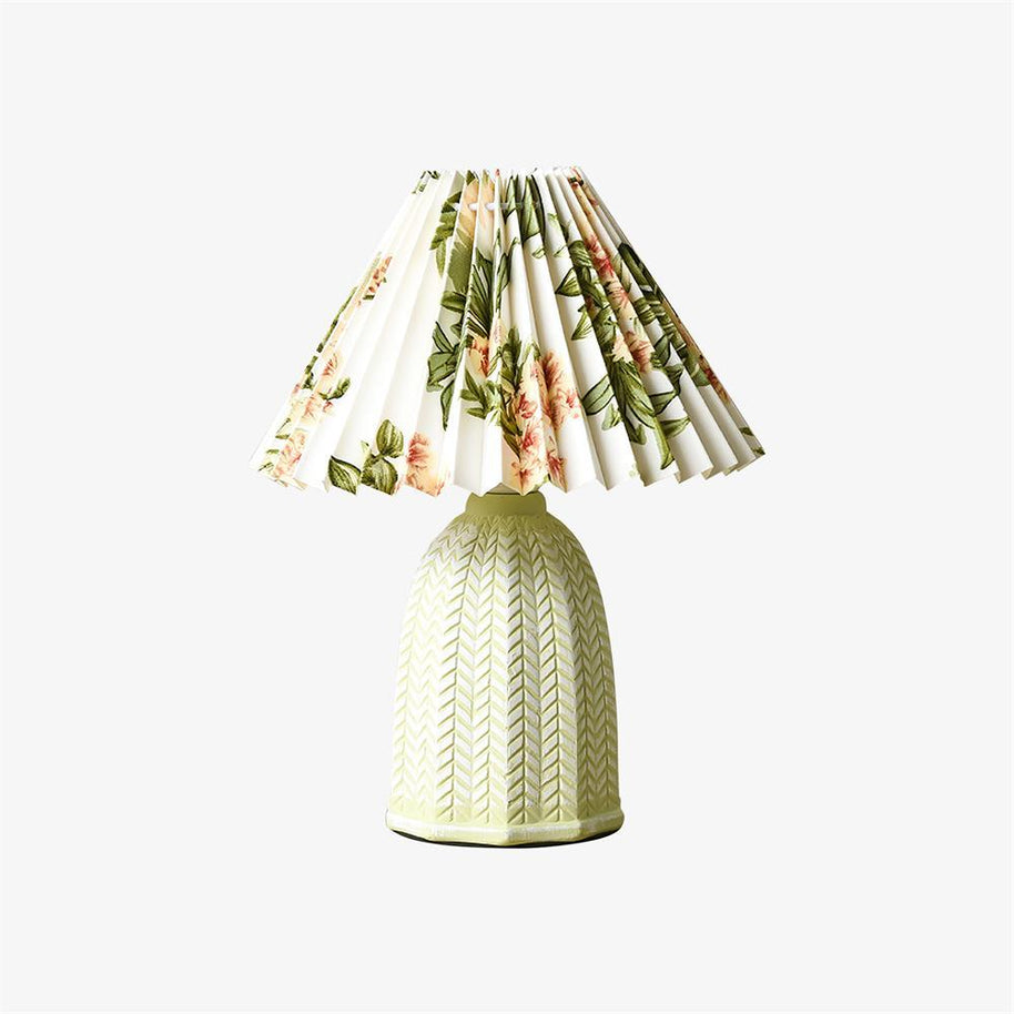 Table lamp with a white pleated shade in a printed floral pattern and a pale green ceramic base with a raised chevron pattern, shown small on a white background.