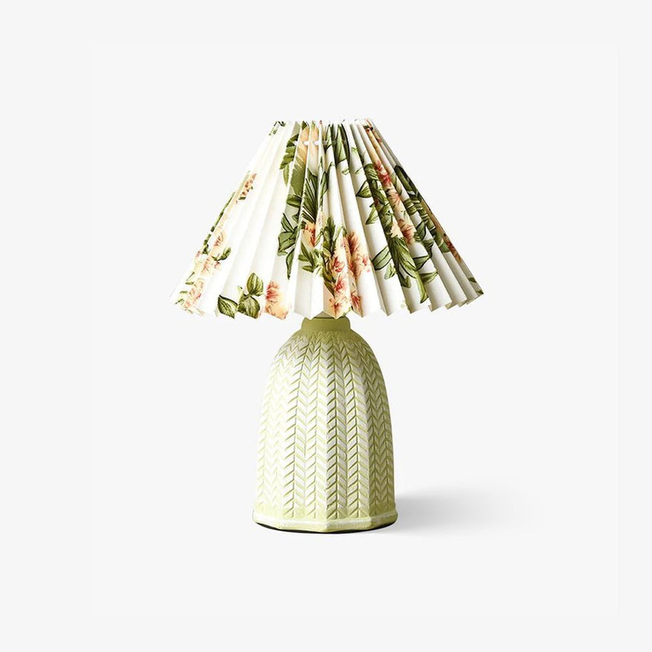 Table lamp with a white pleated shade in a printed floral pattern and a pale green ceramic base with a raised chevron pattern, shown small on a white background.