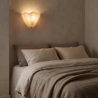 Vela Ribbed Glass Wall Lamp glowing in a bedroom corner at dusk