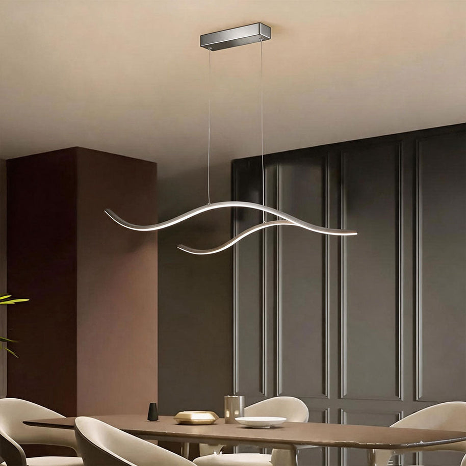 Linear pendant light made of wavy chrome-coloured LED bars hung from a slim rectangular canopy above a dining table beside dark panelling.
