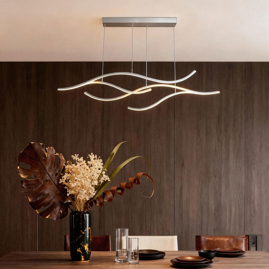 Linear pendant light made of wavy chrome-coloured LED bars hung from a slim rectangular canopy above a table against a walnut-panelled wall.