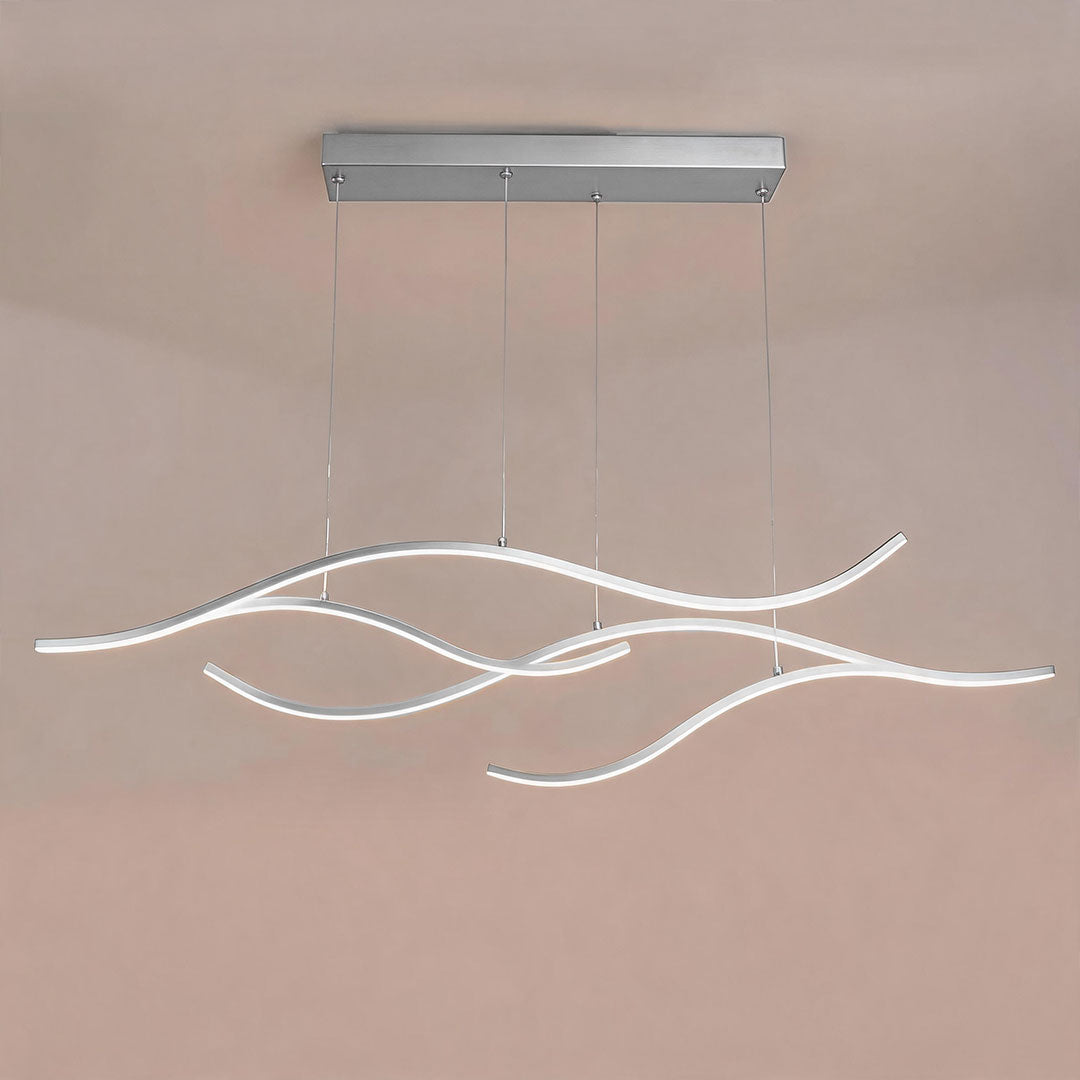 Linear pendant light made of wavy chrome-coloured LED bars hung from a slim rectangular canopy, lit, shown against a plain wall.