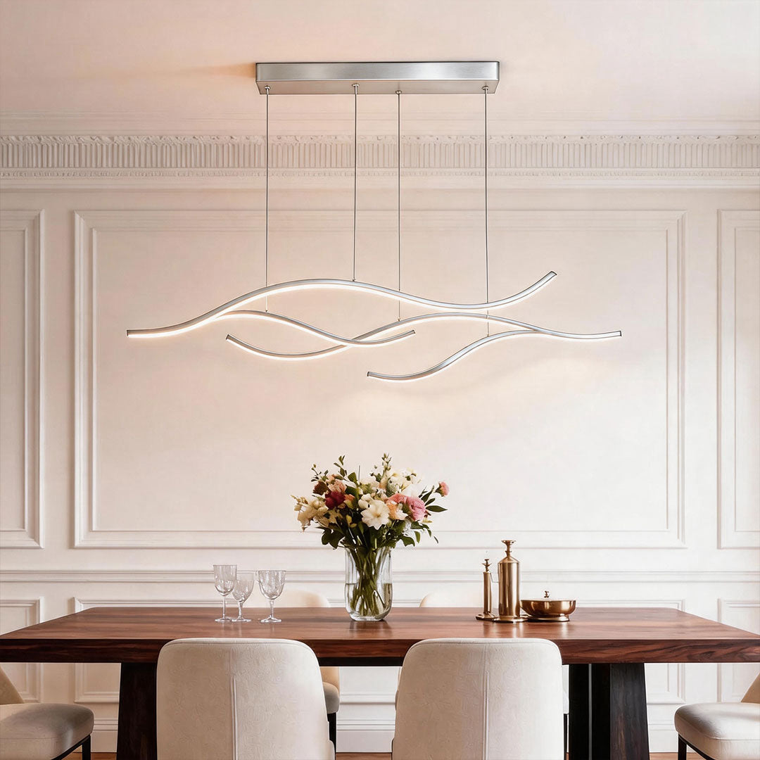 Linear pendant light made of wavy chrome-coloured LED bars hung from a slim rectangular canopy above a dining table in a panelled room.