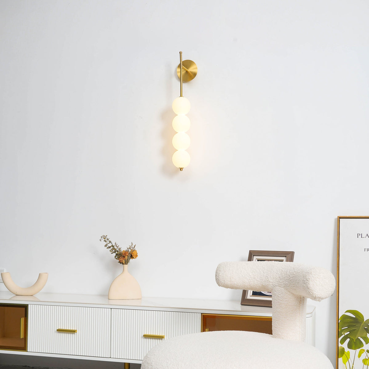 Abaclune Beaded Wall Lamp, Gold lit above white sideboard, room