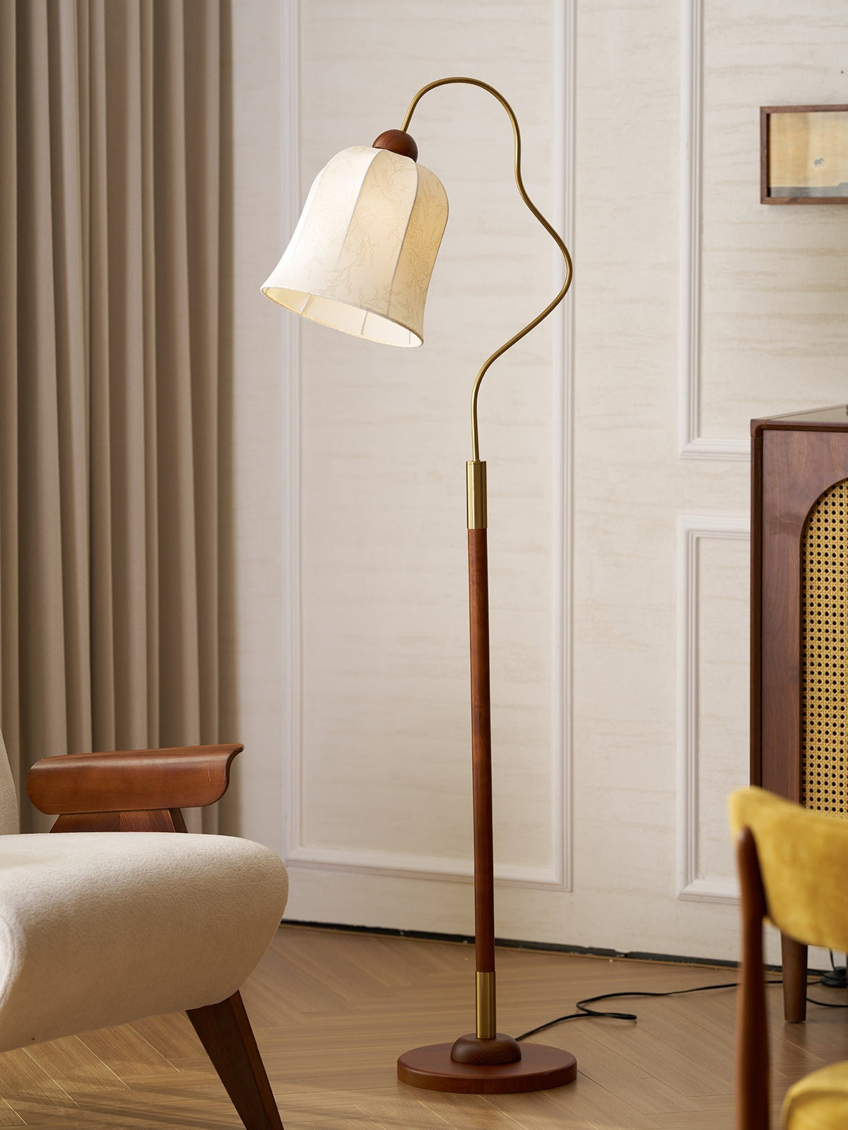 Bellara Floor Lamp in walnut wood and white, unlit, beside an armchair in a paneled room