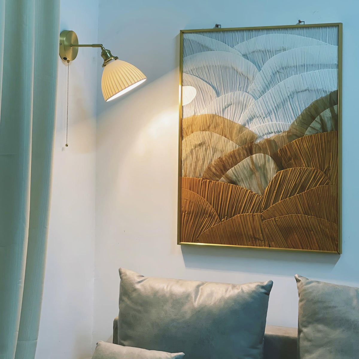 Brasquelle Pleated Ceramic Wall Lamp, lit sconce beside large framed artwork over sofa