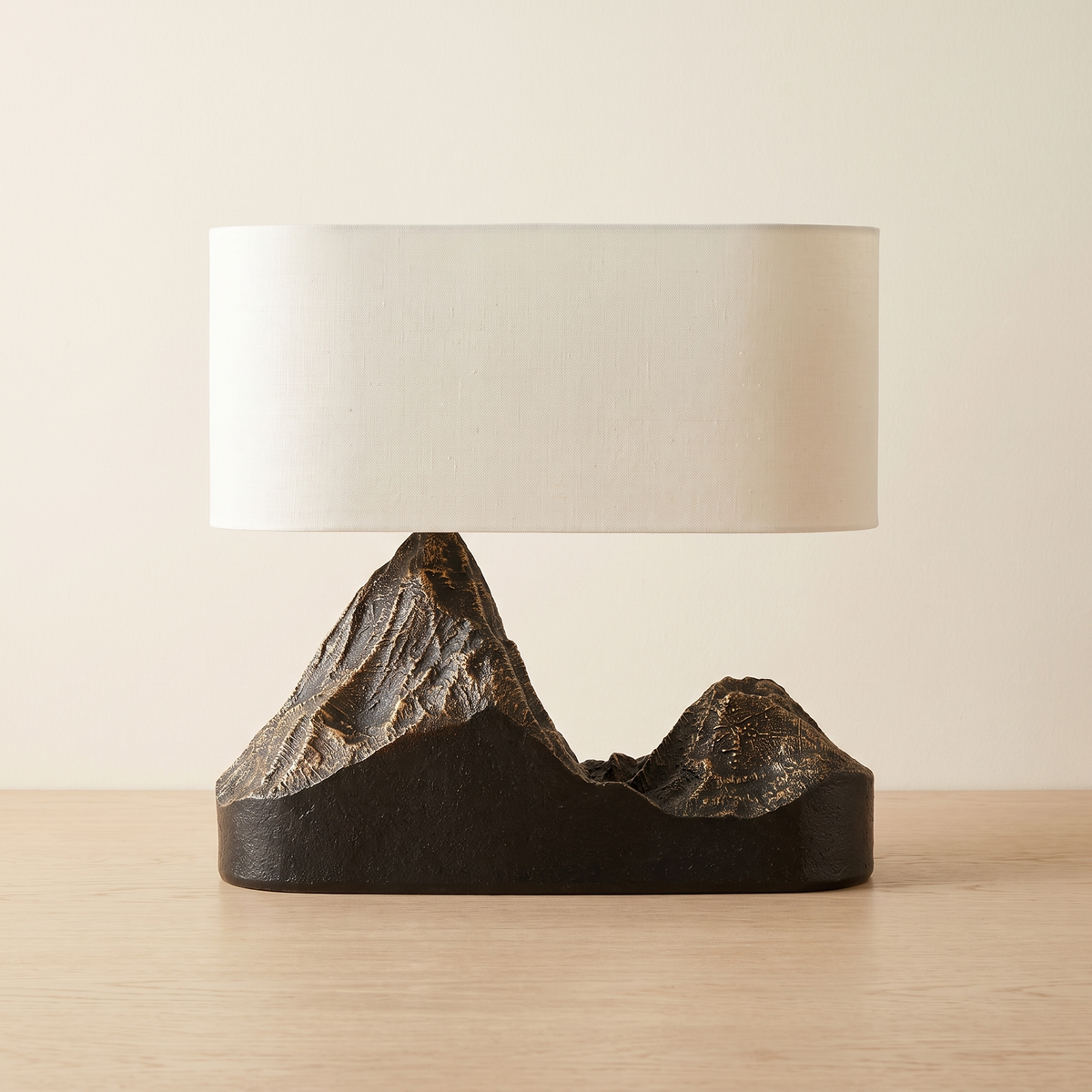 Alpenne Mountain Table Lamp with a cream oval shade on a dark sculpted twin-peak base