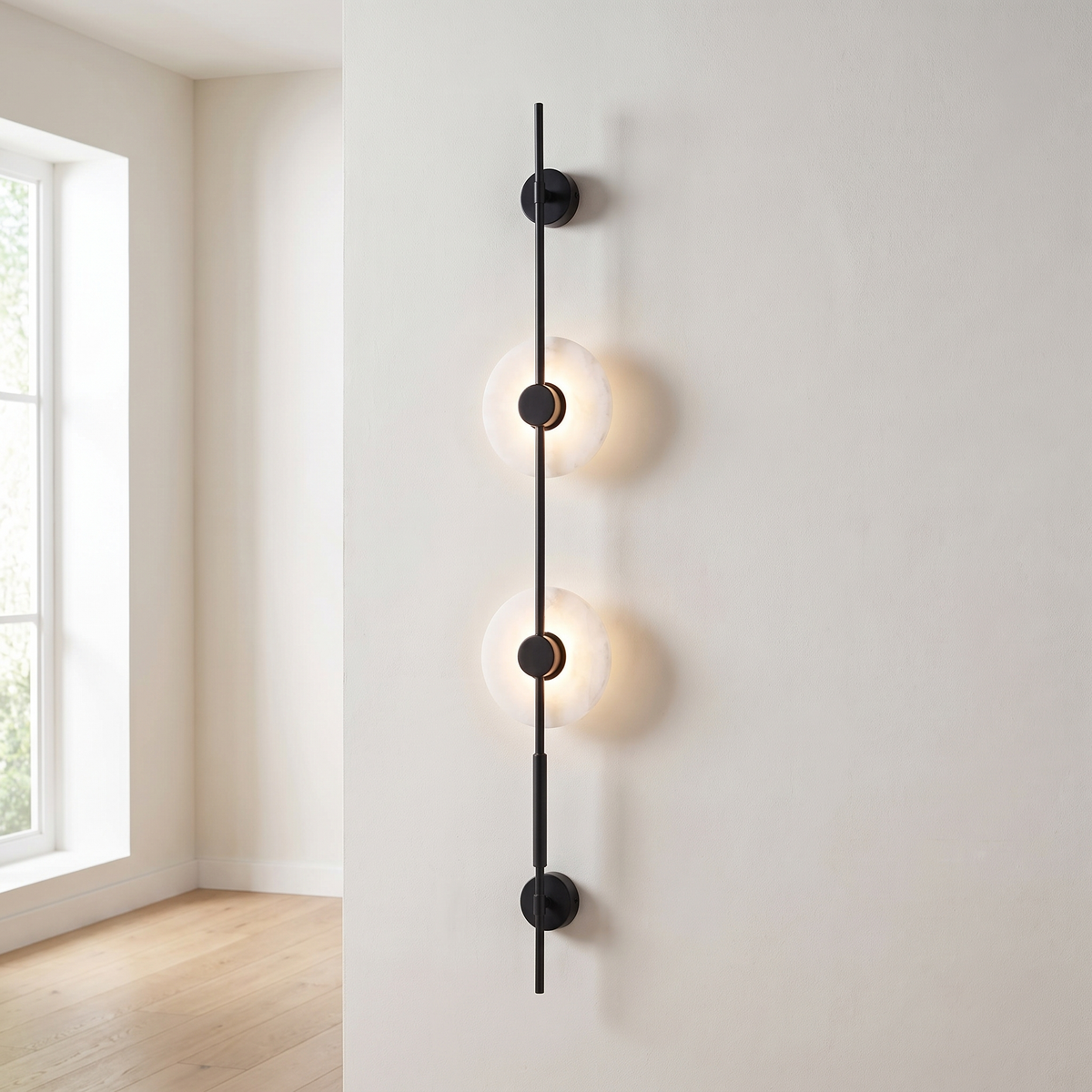 Alvessa Alabaster Disc Wall Light: tall slim vertical matte black rod wall light with 2 round glowing white alabaster discs with black centre caps along the rod and a small black round mount at each end, shown in an entryway