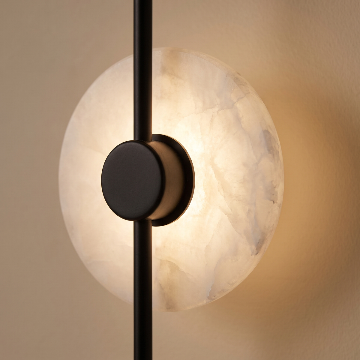 Alvessa Alabaster Disc Wall Light: tall slim vertical matte black rod wall light with 2 round glowing white alabaster discs with black centre caps along the rod and a small black round mount at each end, close-up detail