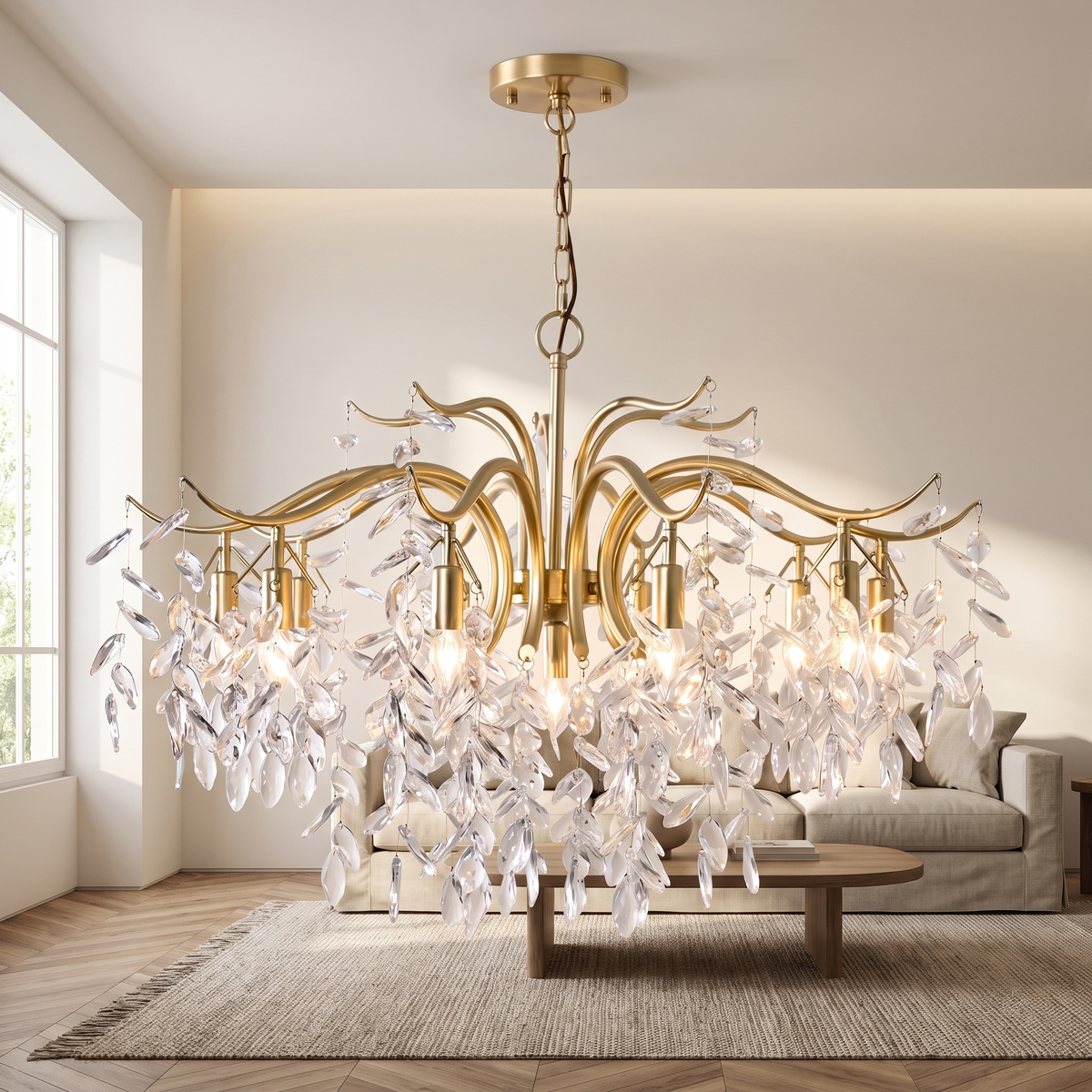 Brancelle Crystal Branch Chandelier: brass chandelier with 7 curved branch-like brass arms hung with clusters of clear crystal leaf drops, suspended from a brass chain and round canopy, shown in a living room