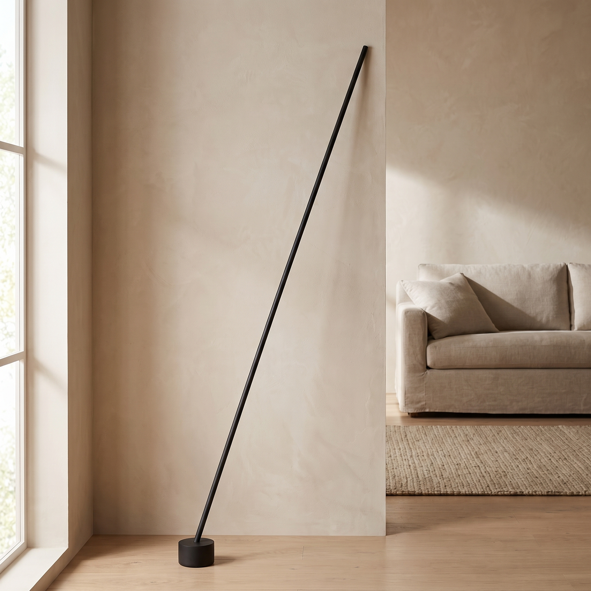 Tensara Elastic Strip Floor Lamp: minimalist floor lamp made of 1 thin straight matte black rod leaning diagonally, its lower end in a small black cylinder floor weight and its top end resting against the wall, shown in a living room