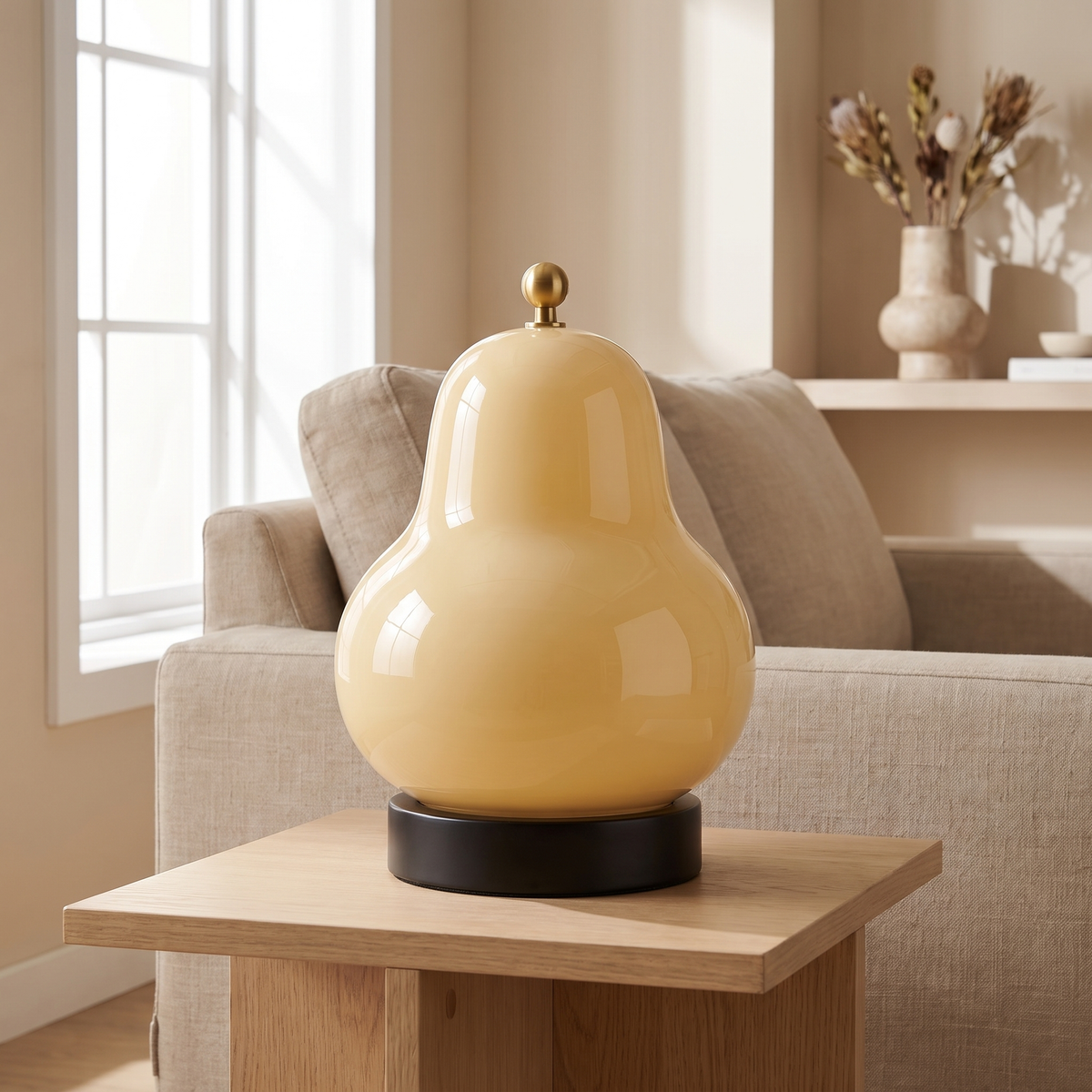 Poiresse Glass Rechargeable Table Lamp: small pear-shaped glossy cream-yellow glass table lamp with a tiny gold finial on top, sitting on a round black base, shown in a living room