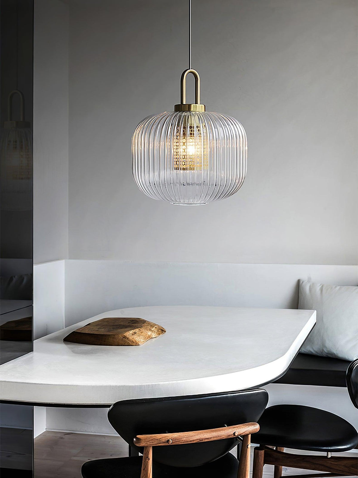 Covelle Pendant Light in gold and clear, round ribbed glass shade lit above a white dining table