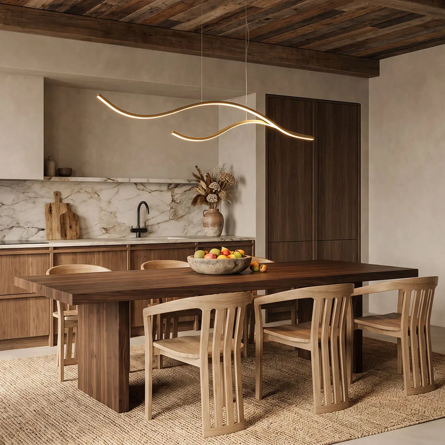 Linear pendant light made of wavy gold-coloured LED bars hung from a slim rectangular canopy above a wooden dining table.
