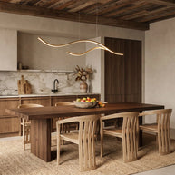 Linear pendant light made of wavy gold-coloured LED bars hung from a slim rectangular canopy above a wooden dining table.