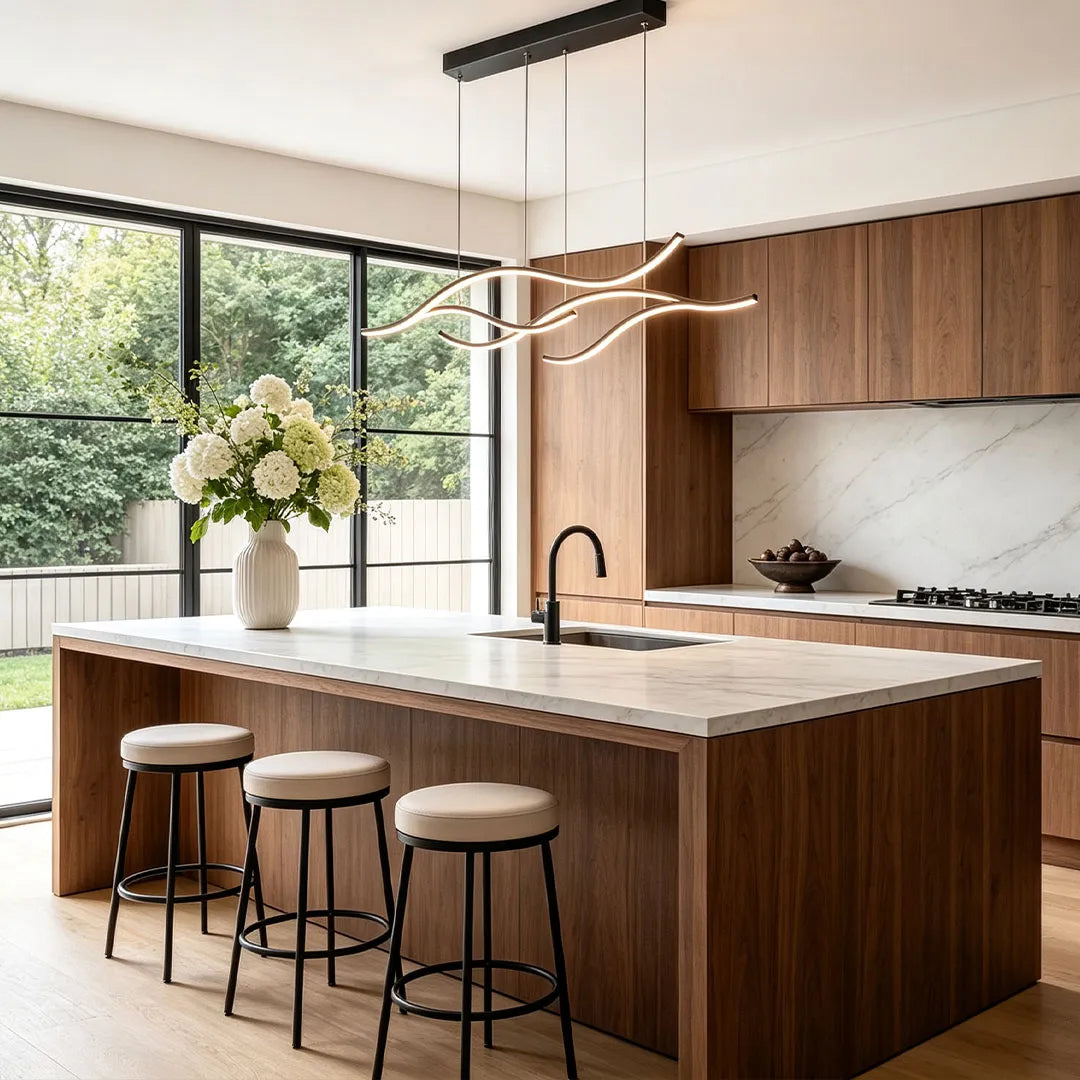 Linear pendant light made of wavy black LED bars hung from a slim rectangular canopy above a kitchen island by a large window.