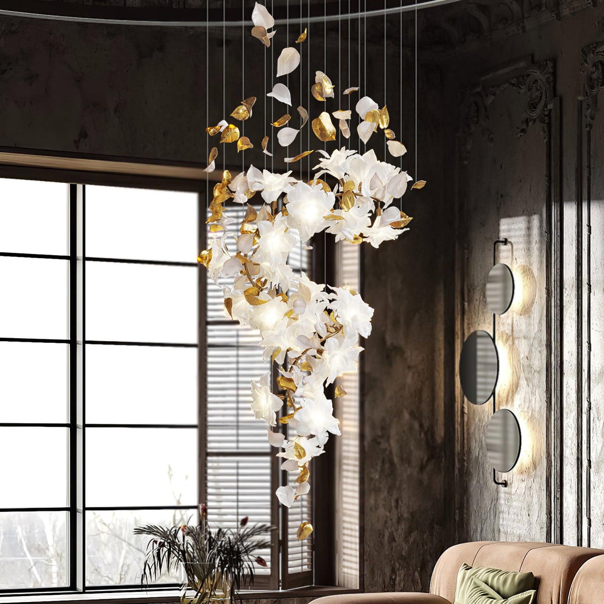 Floravelle Chandelier, spiral cascade of white petals and brass leaves, lit, in a tall room by windows