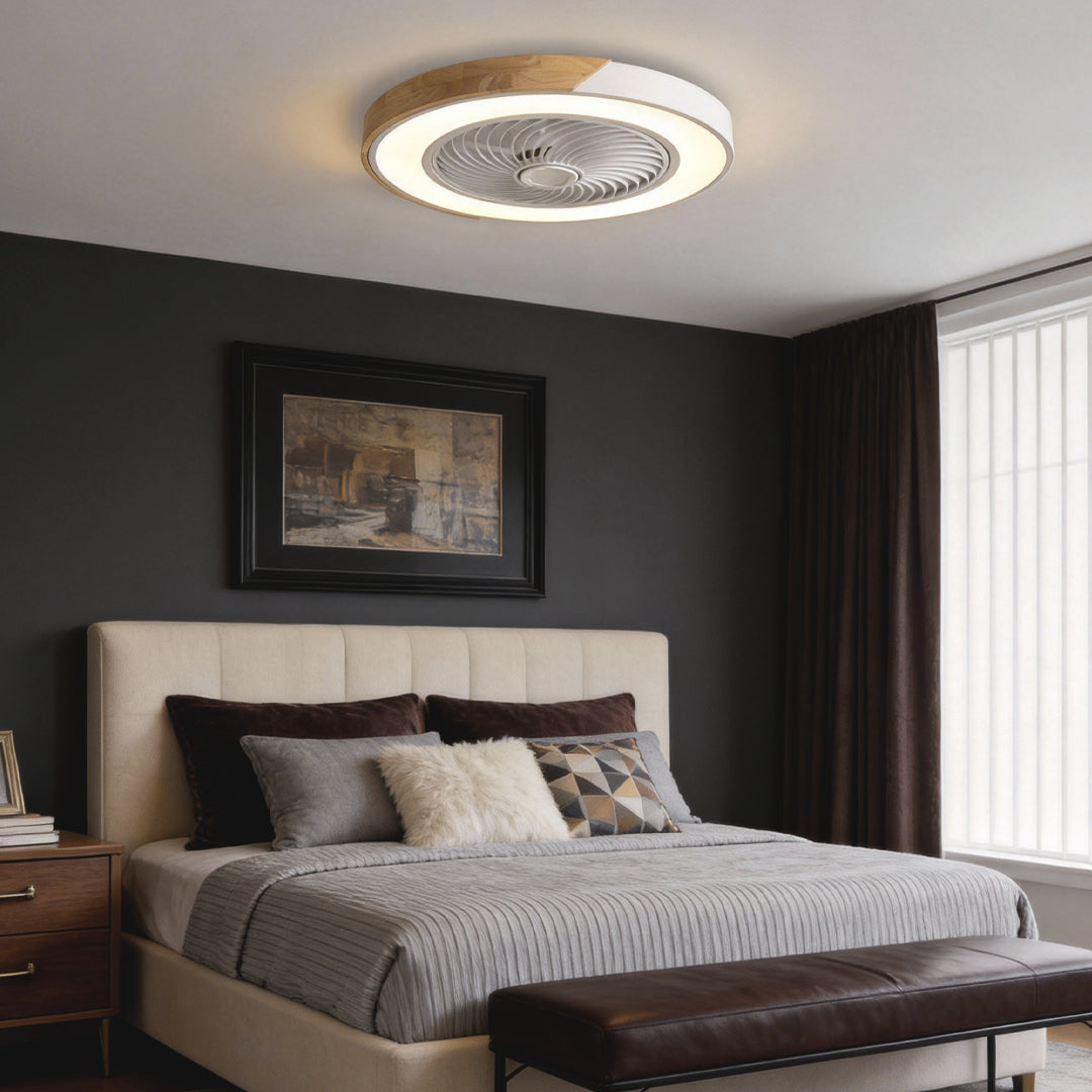 Round white and wood-grain bladeless ceiling fan with light, lit warm, on the ceiling of a bedroom with a charcoal wall.