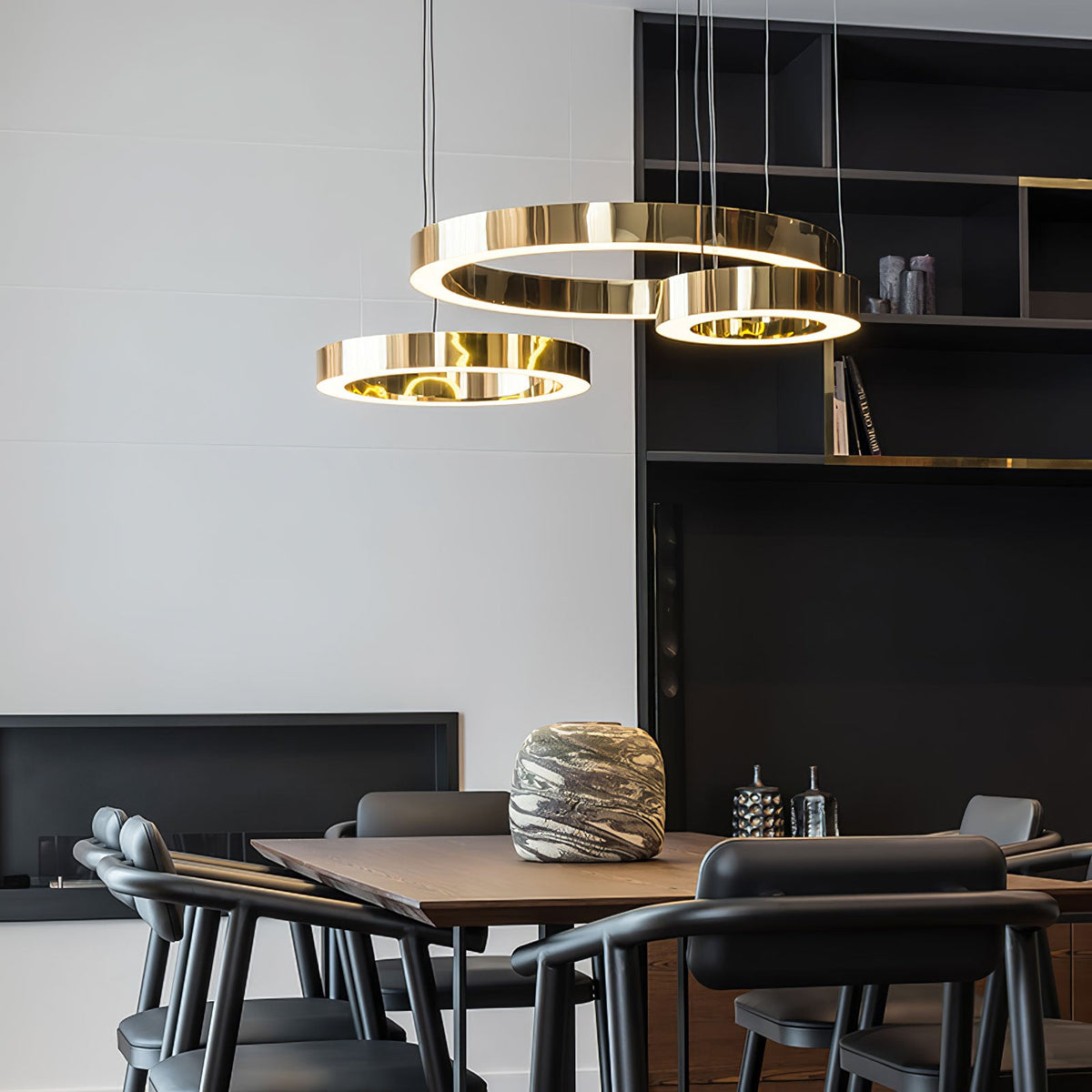 Halorien Ring Pendant Light, three polished gold rings, lit, above a dining table