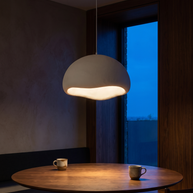 Nuvola cloud pendant glowing warm over a round walnut table at night