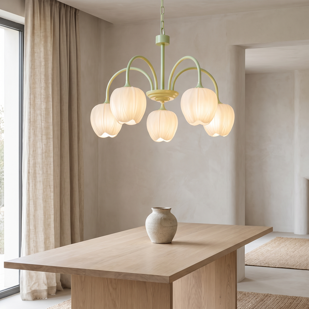 Arcelle chandelier with a matcha green frame and five white tulip-bud glass shades, hanging above a pale oak dining table in a calm room with a linen curtain.