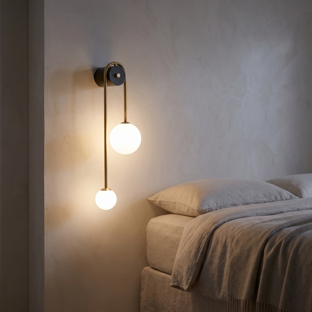Roscelle wall light with a brass arc over a black cylinder body, carrying one large and one small white glass shade.