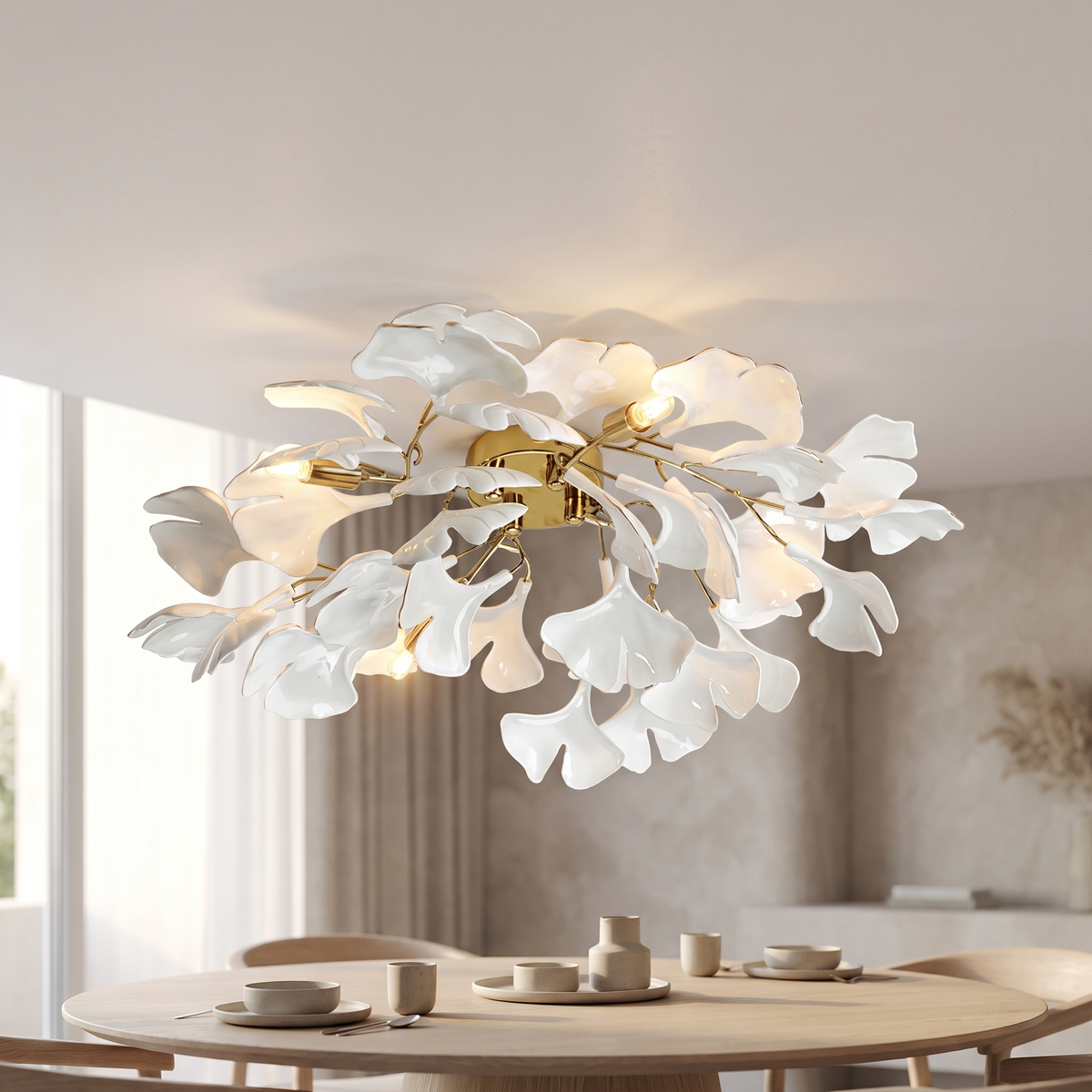 Bellisse ceiling light mounted flush against the ceiling, its gold body carrying gold arms and white ceramic ginkgo leaf shades above a round oak dining table.