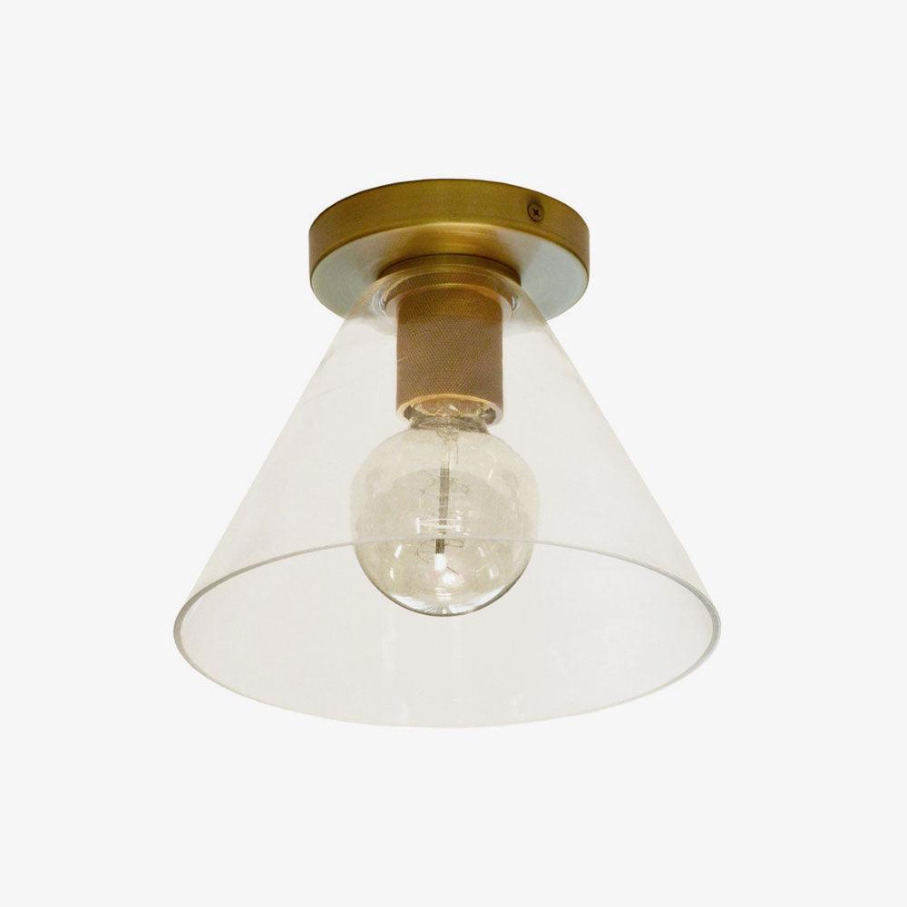 Flush-mount ceiling light with a brass plate and clear cone-shaped glass shade, seen from below.