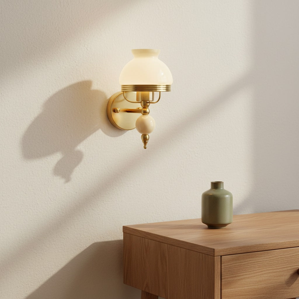 Loressa Glass Wall Light with a beige accent, lit, above a wooden bedside table