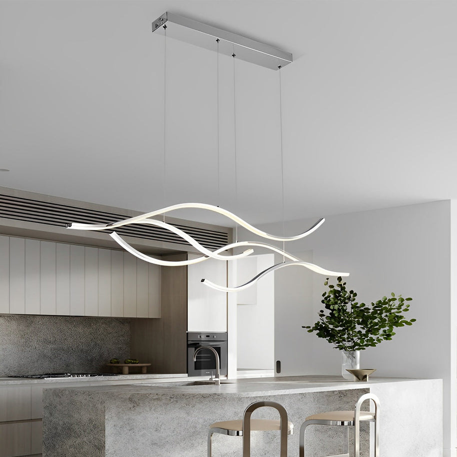 Linear pendant light made of wavy chrome-coloured LED bars hung from a slim rectangular canopy above a stone-topped kitchen island.