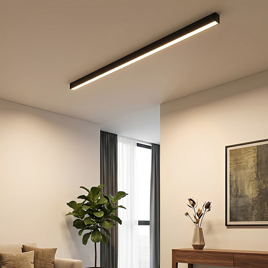 Slim linear LED ceiling light with a black body, fitted across a ceiling near a window.