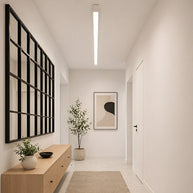 Slim linear LED ceiling light with a white body, fitted along a hallway ceiling.